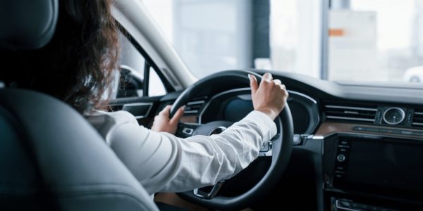 Hands on steering wheel. Beautiful businesswoman trying her new car in the automobile salon.